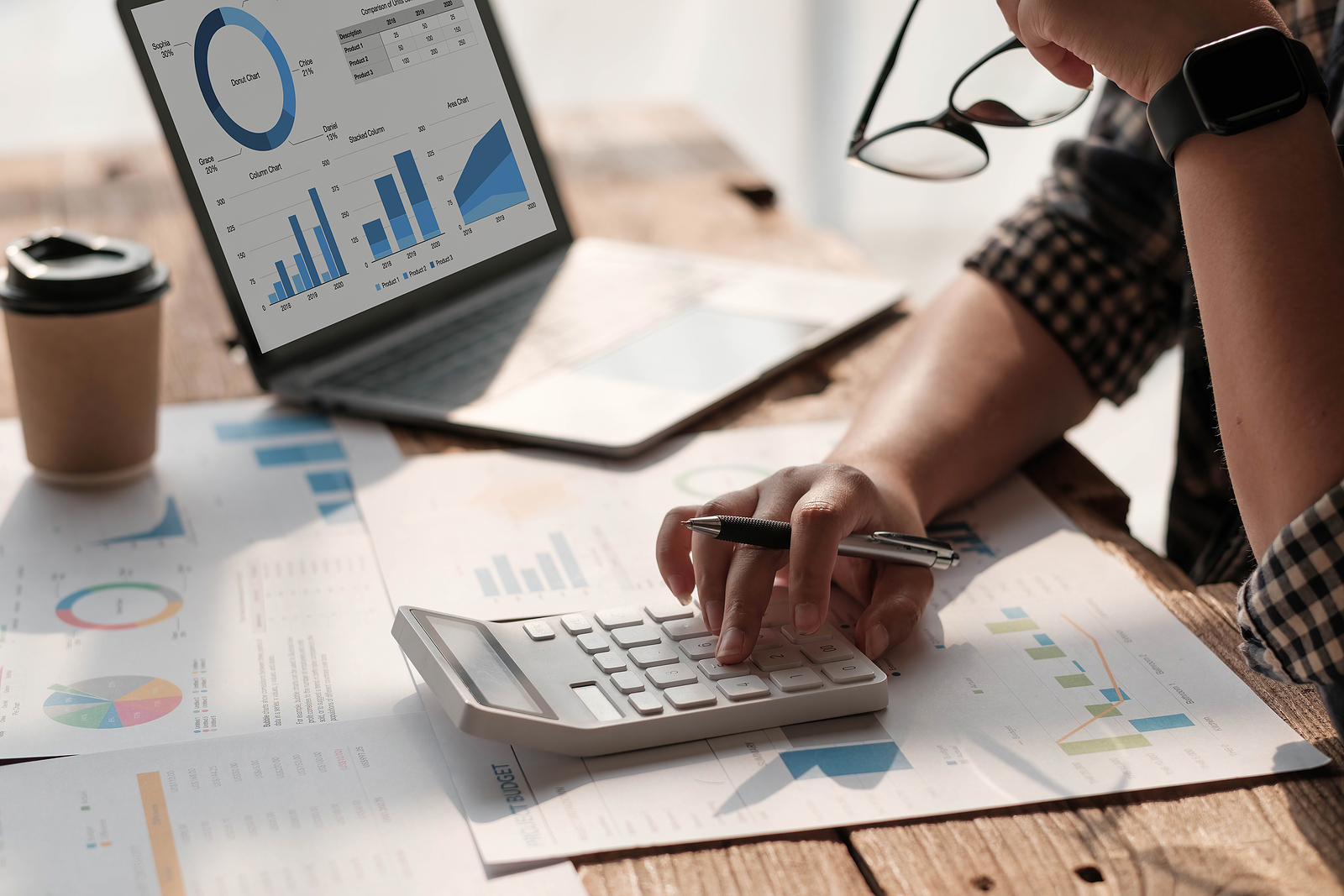 Close up Business woman using calculator and laptop for do math finance on wooden desk in office and business working background, tax, accounting, statistics and analytic research concept.